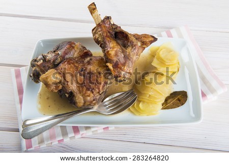 Roasted leg lamb with potatoes on the table of the kitchen