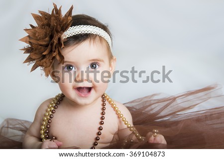 Smiling baby ballerina in brown tutu with a pearl necklace