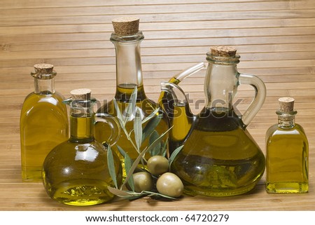 Some bottles of olive oil and some olives on a bamboo mat.
