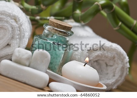 Spa background with bath salts, a towel, a candle and bamboo plants.