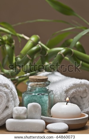 Spa background with bath salts, a towel, a candle and bamboo plants.
