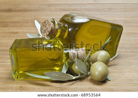 Two bottles of olive oil and some green olives.