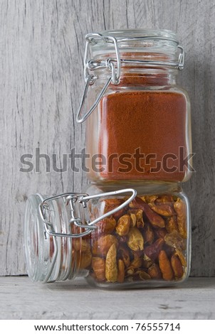 Jars with chilli and paprika on an old wooden stand.