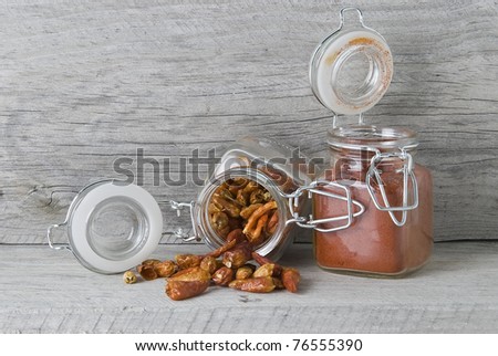 Open jars with chilli and paprika on an old wooden stand.