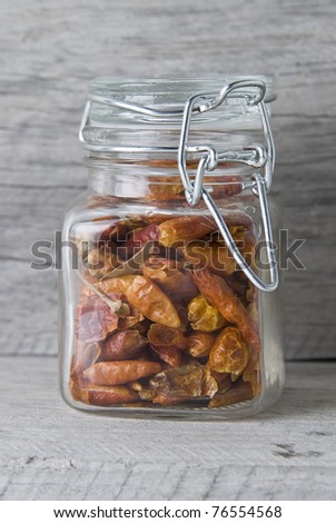 A glass jar with chilli on an old wooden stand.