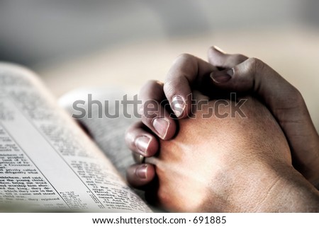 Man\'s hands clasped in prayer over a Holy Bible - represents faith and spirituality in everyday life.