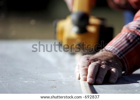 Construction worker planing a piece of wood for a building project.