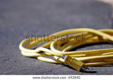 Heavy-duty power cord on black pavement - represents energy and/or power for work.