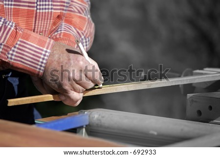 Construction worker measuring wood for a job.