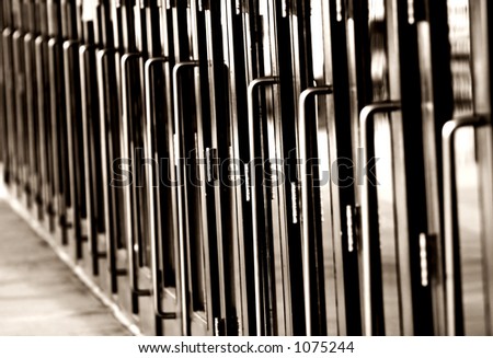 Black & White photo of a long line of steel and glass doors with metal handles (shallow focus).