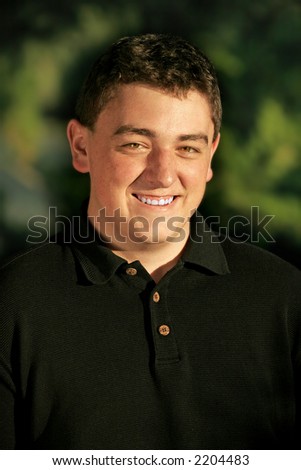 College-aged Caucasian male smiling outdoors in warm-colored, sunset light (shallow focus).