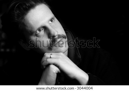 Thoughtful, married man with folded hands (black and white, shallow focus)