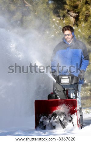 Man using a powerful snow blower in wintertime (shallow focus point on the snow blower).