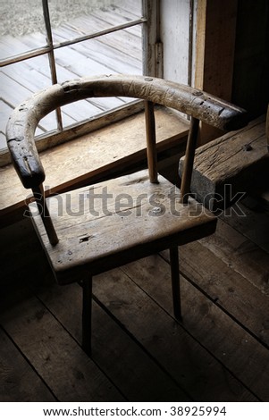 Moody, still life scene of an authentic 19th century hand-made wooden chair in the ambient light of a window.