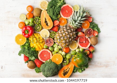 Fruits and vegetables rich in vitamin C background circle shape, oranges mango grapefruit kiwi kale pepper pineapple lemon sprouts papaya broccoli, on white table, top view, selective focus