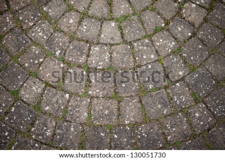 Weathered circular stone background with fragments of grass and soil