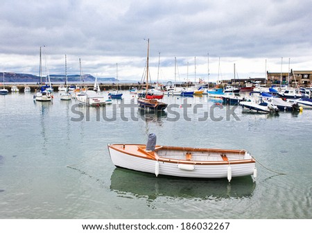 LYME REGIS, ENGLAND - APRIL 08: Boats in high tide, Lyme Regis harbour, Jurassic Coast, Dorset, England, April 08, 2012. The town is famous for the fossils found in the cliffs and beaches.