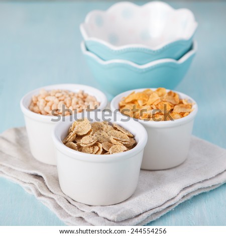 Mixed cereals in the blue bowl with empty bowls on the background, selective focus