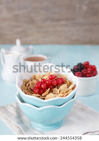 Cereals in the blue bowl with milk, coffee and fruit on the back, selective focus