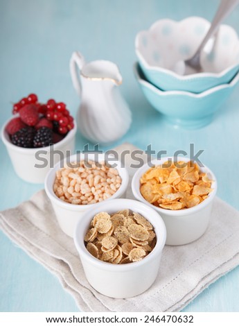Mixed cereals in the blue bowl with milk, empty bowls and fruit, selective focus