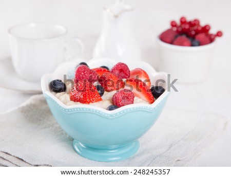 Oats porridge with berries on the white table, selective focus