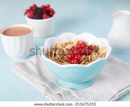 Cereals in the blue bowl with milk, coffee and fruit on the back, selective focus