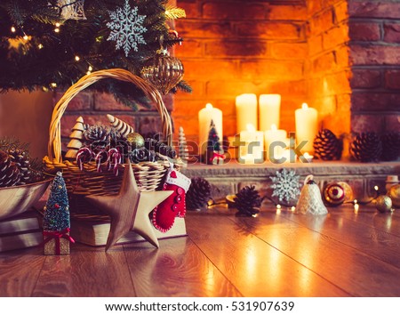 Christmas decorations in the basket in front of the fireplace with candles and baubles, selective focus; dark vintage style toned photo