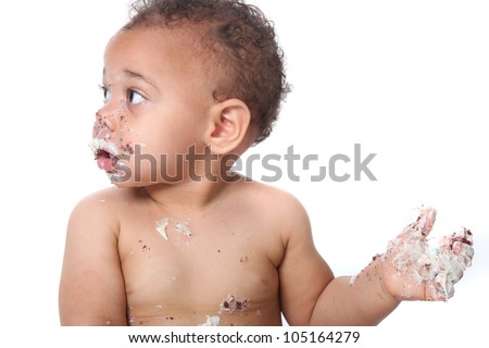 Messy baby boy eating cake on his 1st birthday