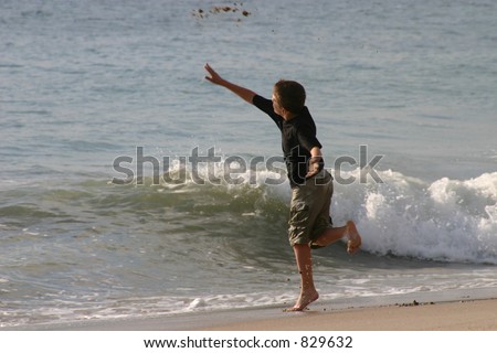 Boy throwing rocks into the ocean