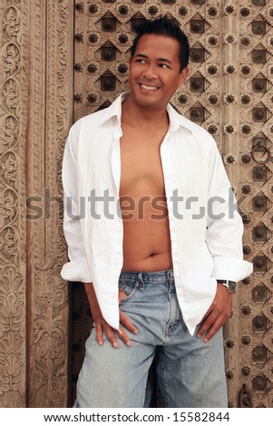 Smiling Happy Asian Male With White Shirt Open and Chest Exposed Wearing Jeans