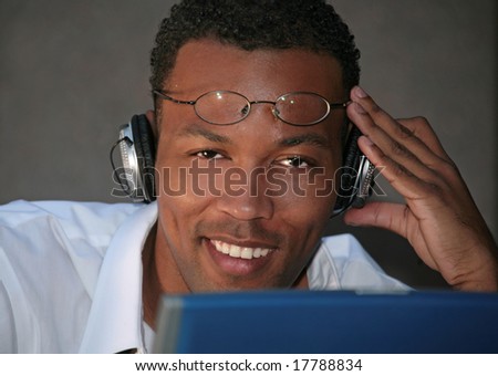 Smiling Black Businessman Listening to Music With Headphones While Working