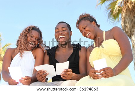 Three African American Friends Outdoors Looking at Photographs and Laughing