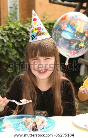 Happy Young Girl Celebrating Her Birthday by Eating Cake
