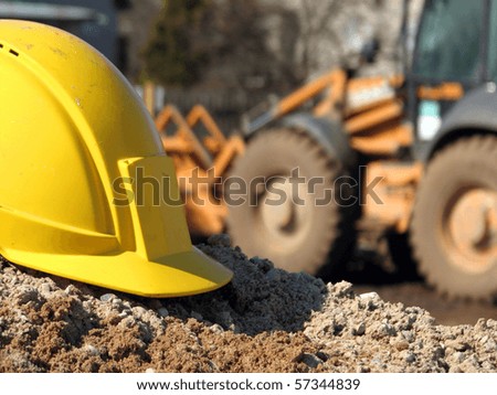 Hard hat on the construction site excavator on the background Hard hat on the construction site excavator on the background