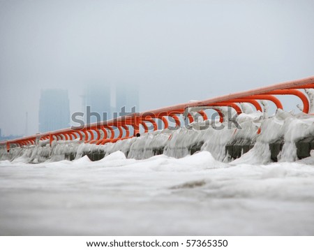 Frozen railings, high-rise buildings on the foggy background