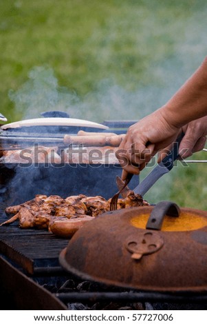 Hands of a cook grilling meat and chicken