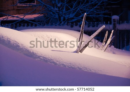 Urban wintry night scene, cars on parking lot screen-wipers sticking out of snow