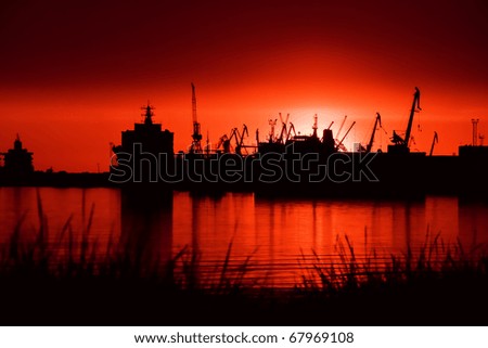 View over the see on port at night, cranes on sunset light
