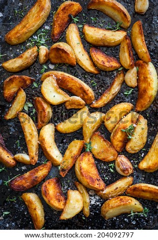 Roasted potato wedges with herbs and garlic on a baking tray