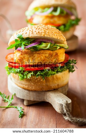 Fish and crab burgers with fresh vegetables on wooden serving boards