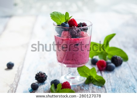 Delicious blackberry,raspberry and blueberry smoothie garnished with fresh berries in glass. soft focus
