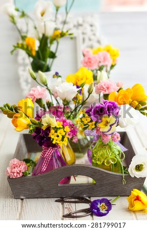 Beautiful fresh flowers in glass bottles on the wooden table