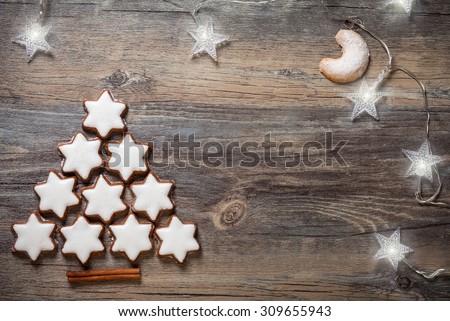 Christmas background with gingerbread cookies,christmas lights and spices on the old wooden board