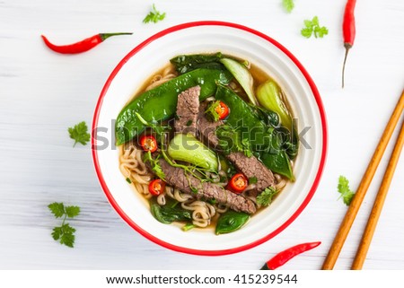 Spicy Asian beef soup with noodles and chinese vegetables