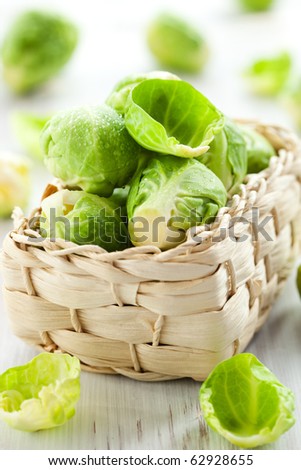 Wet brussels sprouts in basket on the white wooden table