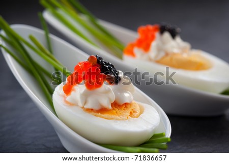 Boiled eggs with red and black  caviar in  spoon