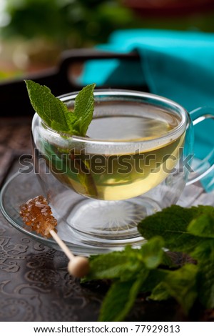 Cup of tea with mint leaves and sugar stir stick