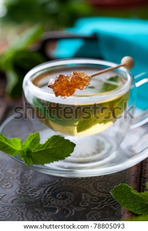 Cup of tea with mint leaves and sugar stir stick