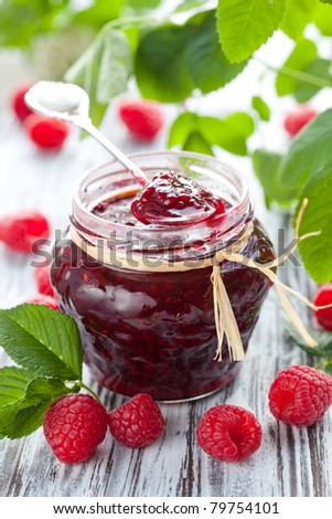 raspberry jam in a jar and fresh berries on the wooden table