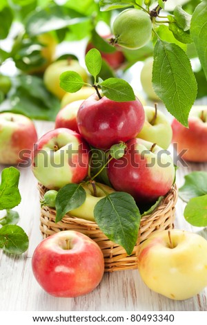 Red,green and yellow apples with leaves in the basket